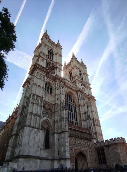 Vista de la fachada principal de la Abadía de Westminster en Londres, con sus dos torres góticas y un cielo azul despejado de fondo