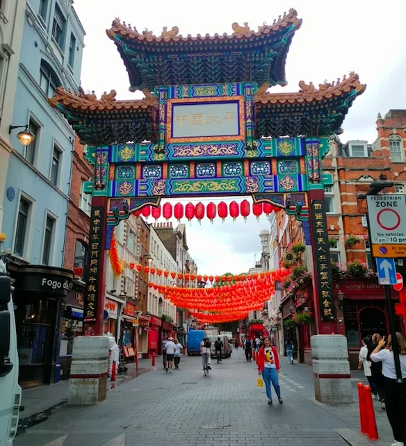 Puerta de entrada de Chinatown en Londres, decorada con farolillos rojos y un arco tradicional chino, con calles peatonales llenas de personas