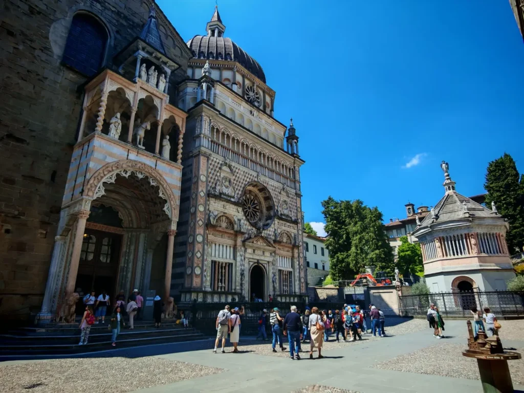 Cappella Colleoni y Baptisterio en la Piazza Duomo de Bérgamo, detalle de la fachada renacentista y visitantes en la plaza.