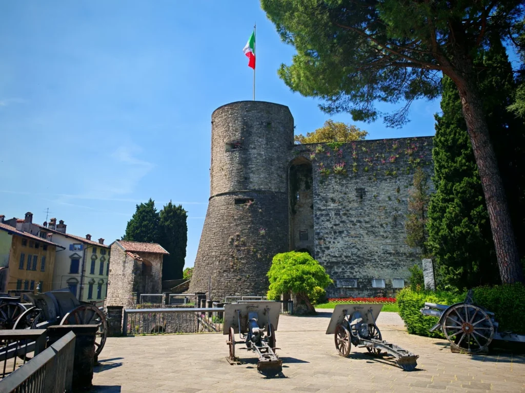 La Rocca de Bérgamo con su torre de piedra, cañones históricos y bandera italiana. Imprescincible que ver en Bérgamo en 1 día