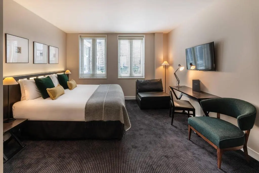 Habitación de hotel en Londres con cama king, sofá, escritorio y TV; alojamiento moderno y luminoso — mejores zonas para alojarse en Londres.