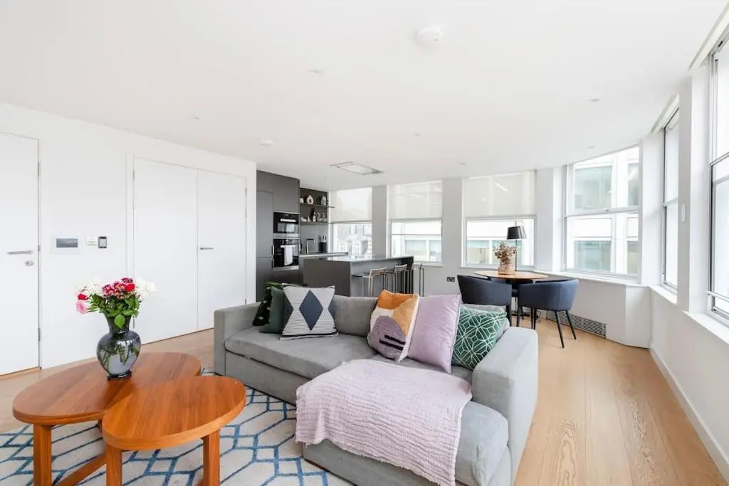 Apartamento donde alojarse en Londres con salón luminoso, cocina integrada y sofá; alojamiento moderno ideal para familias o parejas en el centro.