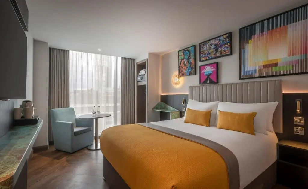 Habitación de hotel moderna en Shoreditch, Londres, con cama king, mesa y arte urbano en las paredes; alojamiento céntrico ideal para parejas.