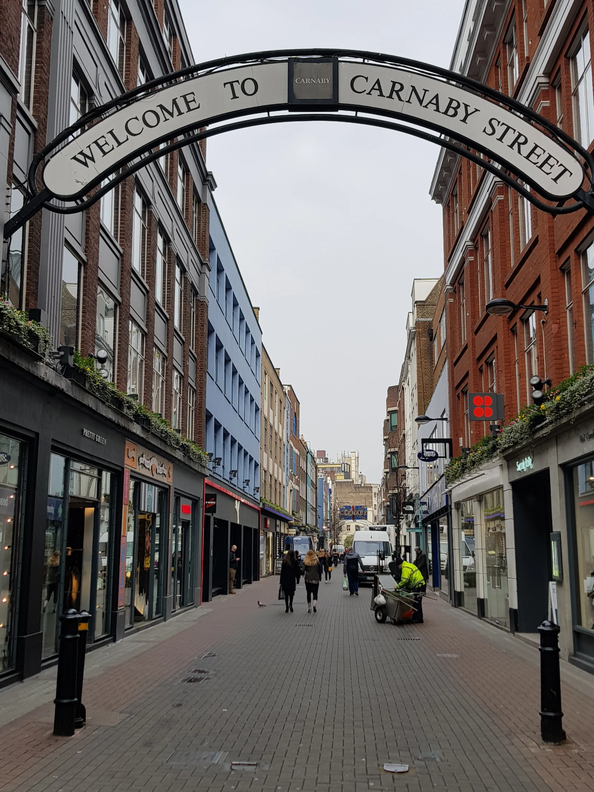 Entrada a Carnaby Street en Londres, con el icónico arco de bienvenida sobre la calle, rodeada de tiendas y un ambiente vibrante