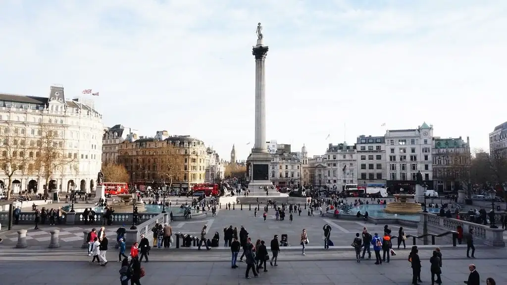Vista panorámica de Trafalgar Square en Londres, con la columna de Nelson en el centro, rodeada de edificios y turistas disfrutando del día