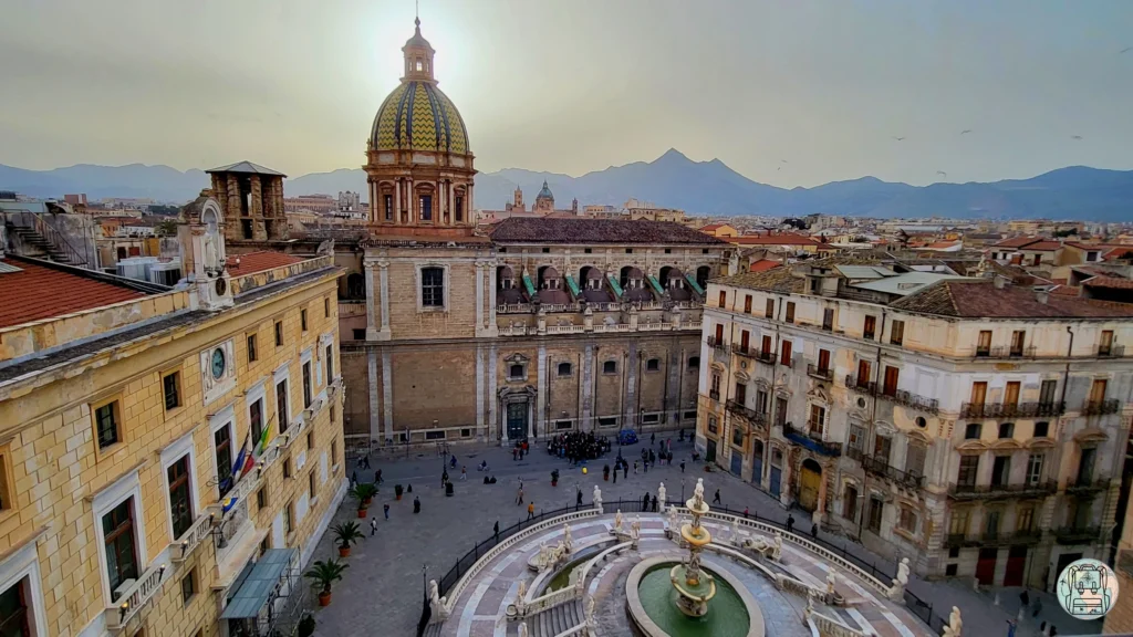 Turismo en Palermo, Italia: la Piazza Pretoria y su fuente monumental, un destino cultural ideal para visitar en febrero. Arquitectura histórica siciliana con montañas al fondo